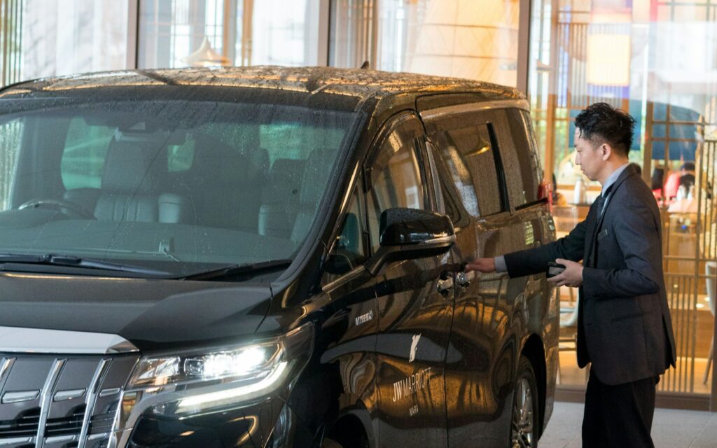 Private chauffeur in a suit standing next to a black car