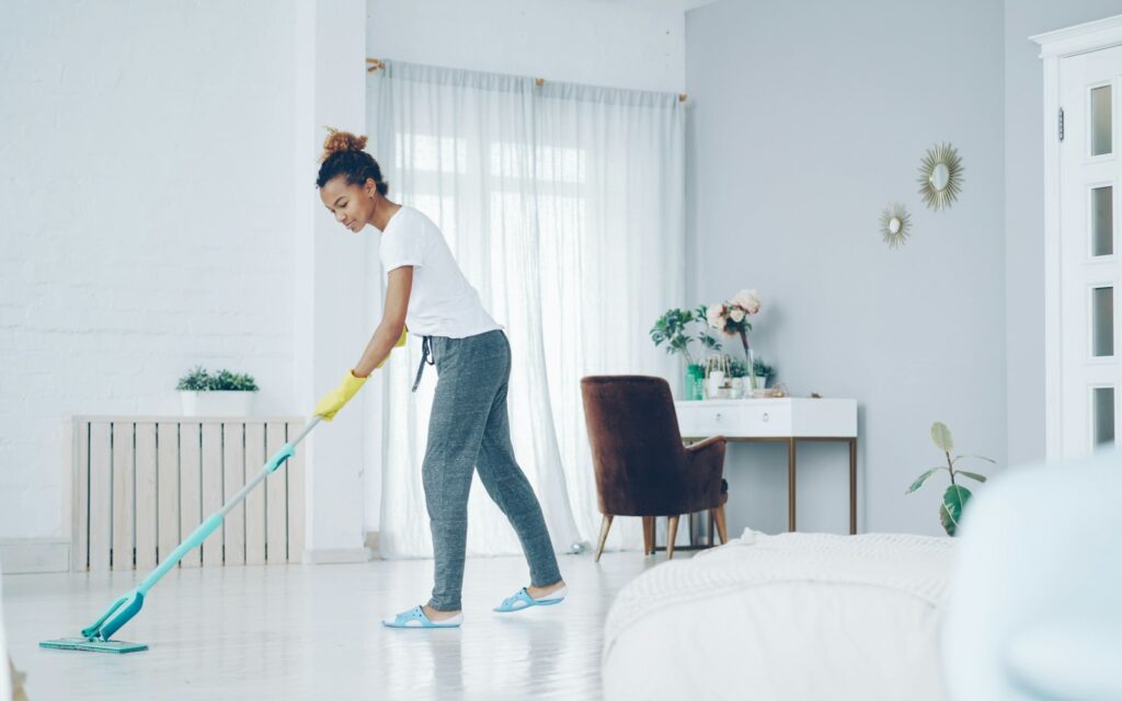 Housekeeper mopping the floor of a bright modern living room