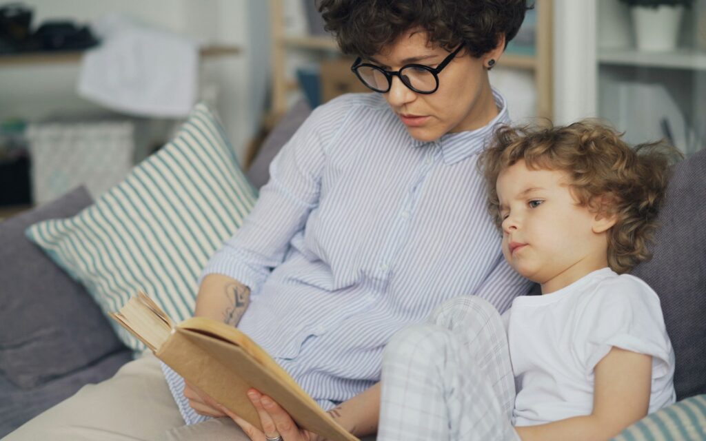 Nanny reading a book to a child on a couch